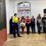 Die Künstlerin Tiziana Krüger steht im Ausstellungsraum und spricht zu einem Publikum.