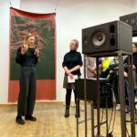 Die Künstlerin Bea Targosz und die Kunsthistorikerin Julia Meyer-Brehm stehen im Ausstellungsraum vor und zwischen Kunstwerken. Sie sprechen zu einem Publikum.