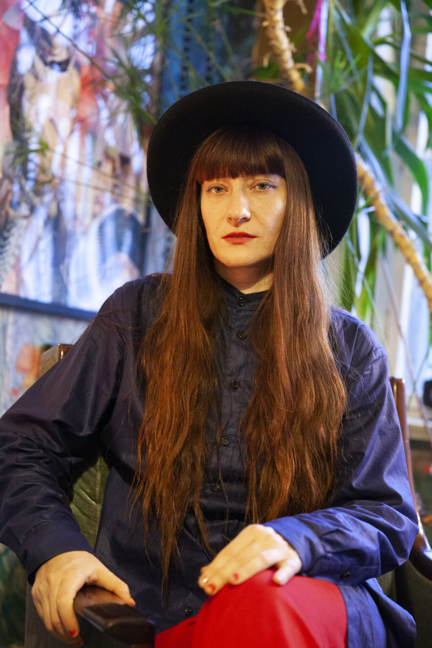 Porträtfoto von Viviana Druga. Die Künstlerin trägt einen Hut und schaut direkt in die Kamera.