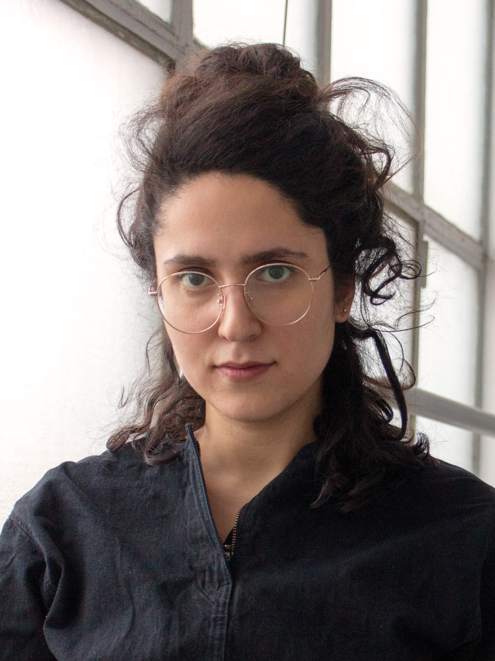 Porträtfoto von Wagehe Raufi. Die Künstlerin trägt eine Brille und schaut frontal in die Kamera.